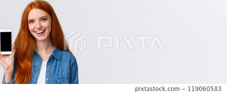 Close-up portrait modern millennial cute redhead female with blue eyes, advice get cool new app, showing smartphone display and smiling, advertising game or photo filter application Close-up portrait modern millennial cute redhead female with blue eyes, advice get cool new app, showing smartphone display and smiling, advertising game or photo filter application 119060583