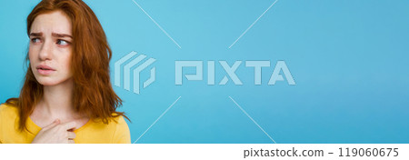 Headshot Portrait of happy ginger red hair girl with freckles smiling looking at camera. Pastel blue background. Copy Space 119060675