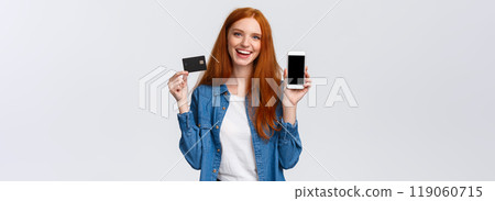 Shopping, application and mobile concept. Waist-up portrait friendly charismatic female blogger, redhead girl promote bank service, showing smartphone or app on display and credit card, smiling 119060715
