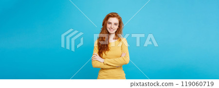 Portrait of young beautiful ginger woman with freckles cheerfuly smiling looking at camera. Isolated on pastel blue background. Copy space. 119060719