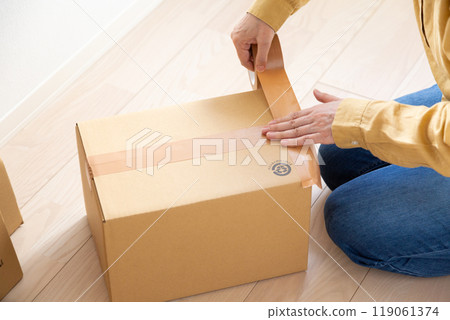 一位中年至老年婦女，製作大量用於搬家的紙板。 119061374