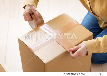 一位中年至老年婦女，製作大量用於搬家的紙板。 119061375