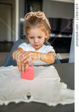 Little girl with a stamp with a name for signing children's things. Identification of personal clothing. Little girl with a stamp with a name for signing children's things. Identification of personal clothing. 119061874