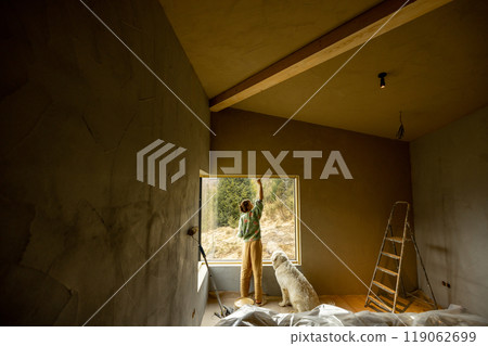 Woman paints walls while making repairment of a new house Woman paints walls while making repairment of a new house 119062699