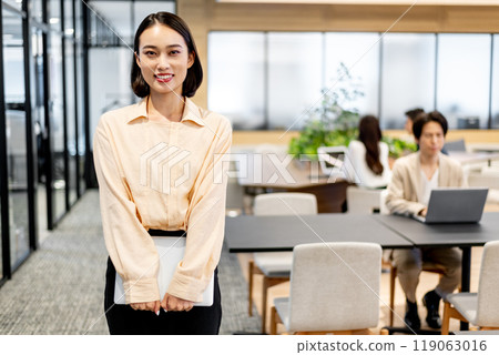 A business person holding a computer with both hands and facing forward with a smile 119063016