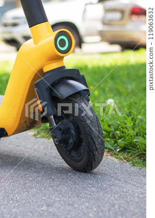A bright yellow scooter is parked neatly on the side of the road A bright yellow scooter is parked neatly on the side of the road 119063632