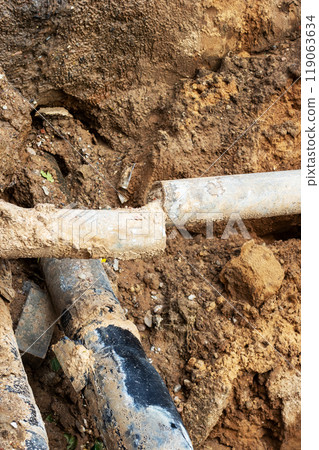 A broken pipe is currently lying in the dirt, waiting to be fixed 119063634