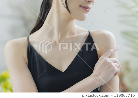A woman in a black camisole dress standing by the window A woman in a black camisole dress standing by the window 119063710