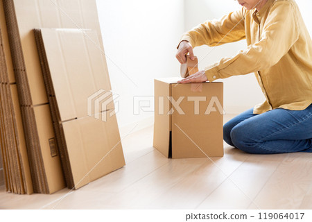 一位中年至老年婦女，製作大量用於搬家的紙板。 119064017