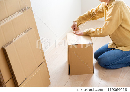 一位中年至老年婦女,製作大量用於搬家的紙板。 一位中年至老年婦女,製作大量用於搬家的紙板。 119064018
