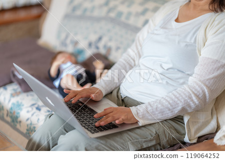 A woman enjoying online shopping alongside her child A woman enjoying online shopping alongside her child 119064252