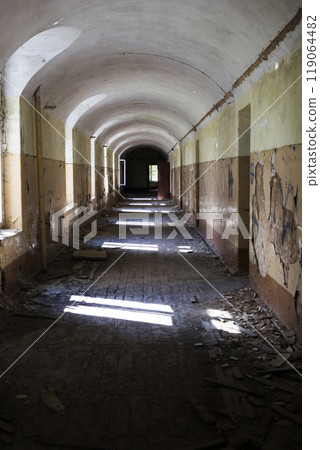 A lengthy corridor within an abandoned structure featuring arched ceilings 119064482
