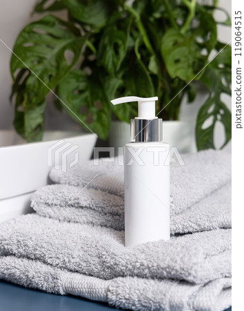 White cosmetic pump bottle on light grey towel near vessel basin close up in bathroom, mockup 119064515