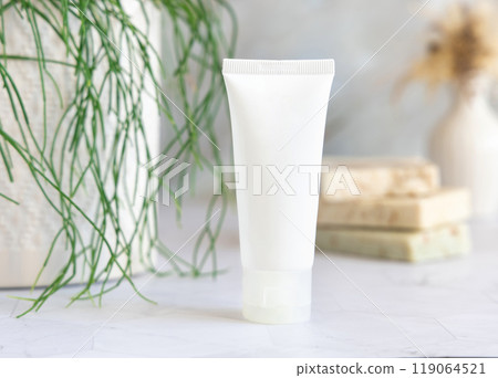 White cream squeeze tube on marble countertop near green plant close up, cosmetic mockup White cream squeeze tube on marble countertop near green plant close up, cosmetic mockup 119064521