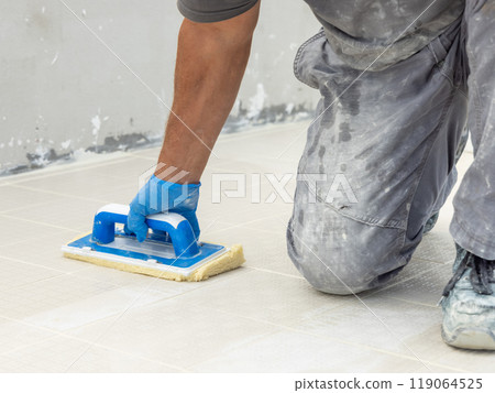 Craftsman in grey work clothes washing surface with a float during construction 119064525