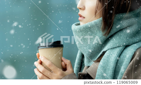A woman drinking a hot drink on a snowy winter street corner A woman drinking a hot drink on a snowy winter street corner 119065009