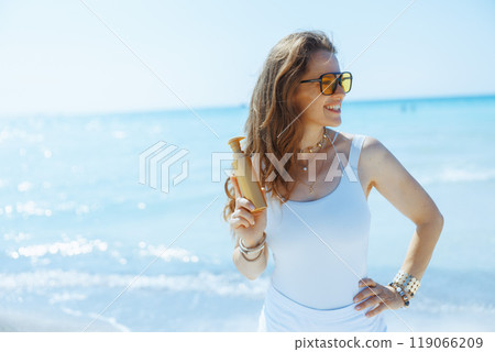 smiling stylish female on seashore with spf smiling stylish female on seashore with spf 119066209