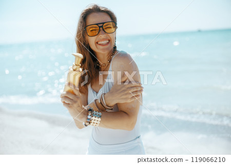 smiling stylish woman on seacoast with sunscreen 119066210