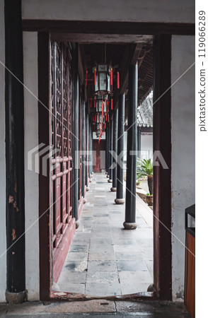 A quiet hallway in a traditional Chinese courtyard featuring red lanterns along stone flooring A quiet hallway in a traditional Chinese courtyard featuring red lanterns along stone flooring 119066289