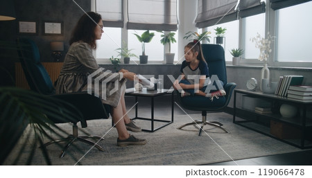 Female child psychologist shows illustrations to Asian school-aged girl 119066478