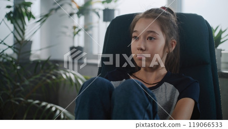 Upset Asian school-aged girl talks to child psychologist during counseling session 119066533