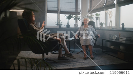 Female psychotherapist and elderly woman patient laugh during meeting 119066611