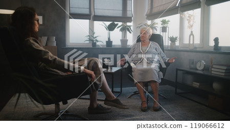 Female psychotherapist and elderly woman patient laugh during meeting 119066612