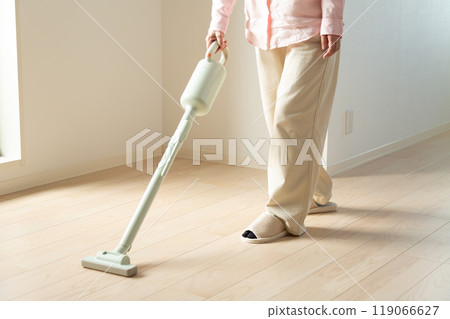 Middle-aged to senior women vacuuming 119066627