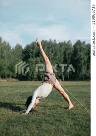 Adult female practising yoga outside in crop top and linen shirts 119066739