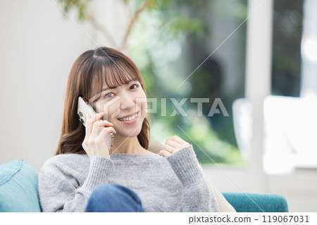 坐在沙發上打電話的女人 119067031