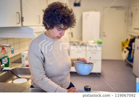 a young plus size woman prepares pasta with bacon in a shared kitchen in a student dormitory a young plus size woman prepares pasta with bacon in a shared kitchen in a student dormitory 119067092