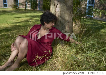 a young plus-size woman in a burgundy dress is playing in the garden of a student dormitory 119067116