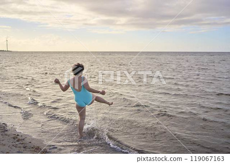 a young plus-size woman is engaged in winter swimming and warming up by the sea 119067163