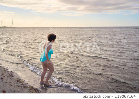 a young plus-size woman is engaged in winter swimming and warming up by the sea a young plus-size woman is engaged in winter swimming and warming up by the sea 119067164