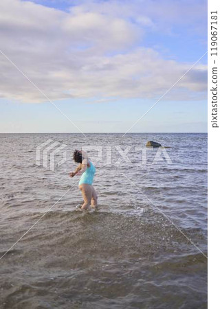 a young plus-size woman is engaged in winter swimming and warming up by the sea a young plus-size woman is engaged in winter swimming and warming up by the sea 119067181