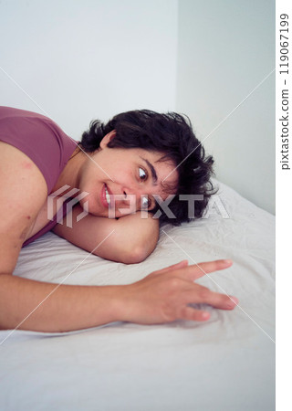 playful young plus size woman in home clothes on bed in student dormitory playful young plus size woman in home clothes on bed in student dormitory 119067199