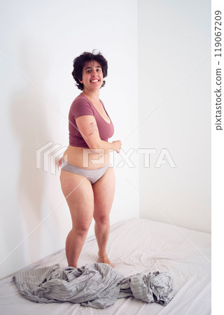 playful young plus size woman in home clothes on bed in student dormitory playful young plus size woman in home clothes on bed in student dormitory 119067209