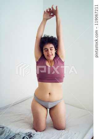 playful young plus size woman in home clothes on bed in student dormitory playful young plus size woman in home clothes on bed in student dormitory 119067211