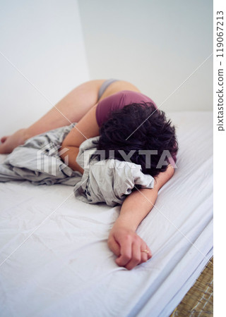 tired young plus size woman in home clothes  on bed in student dormitory 119067213