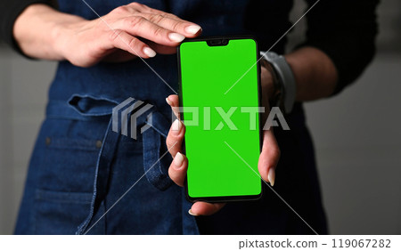 Girl In Apron Holding A Smartphone With Chromakey Green Screen Girl In Apron Holding A Smartphone With Chromakey Green Screen 119067282