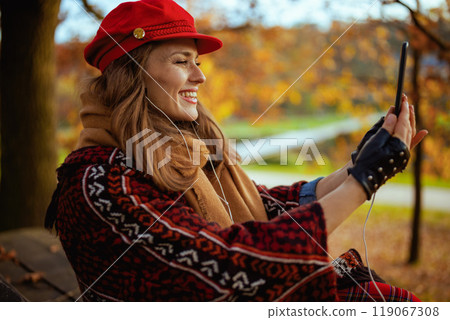 woman video chatting while sitting on bench in city park 119067308