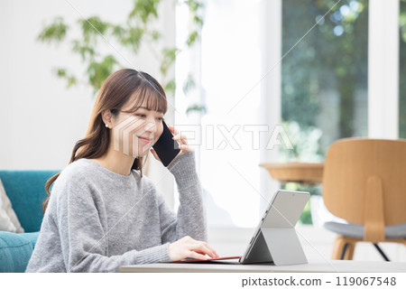 Woman making a phone call while operating a computer 119067548