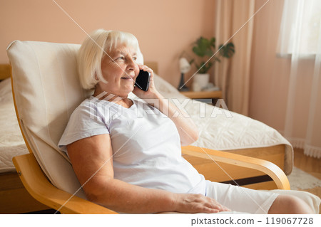 Attractive successful elderly woman using mobile talking on a cellphone while relaxing at home. Attractive successful elderly woman using mobile talking on a cellphone while relaxing at home. 119067728