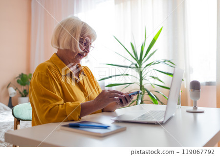 Elderly woman working on laptop computer, smiling, working from home. Trendy woman working on laptop from home 119067792
