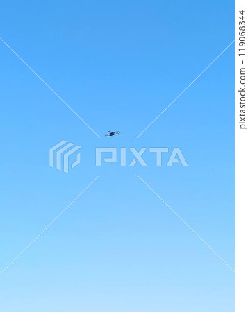 A drone hovers against a backdrop of clear blue sky, likely surveying the area or capturing images for mapping or monitoring purposes A drone hovers against a backdrop of clear blue sky, likely surveying the area or capturing images for mapping or monitoring purposes 119068344