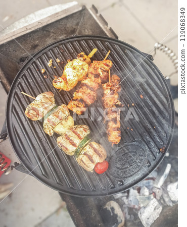 Grilling assorted meat skewers outdoors in a backyard setting on a sunny afternoon Grilling assorted meat skewers outdoors in a backyard setting on a sunny afternoon 119068349