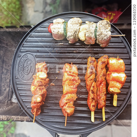 Grilling assorted meat skewers outdoors in a backyard setting on a sunny afternoon 119068350