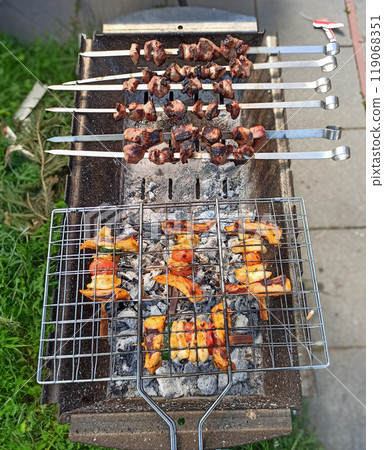 Delicious skewers grilling over charcoal in a backyard setting during a sunny afternoon 119068351