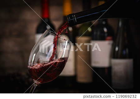 Pouring Red Wine into Glass with Bottles and Grapes Pouring Red Wine into Glass with Bottles and Grapes 119069232