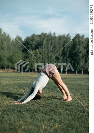 Adult female practising yoga outside in crop top and linen shorts 119069271